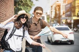 Asian backpack couple tourist holding city map crossing the road - travel people vacation lifestyle concept photo