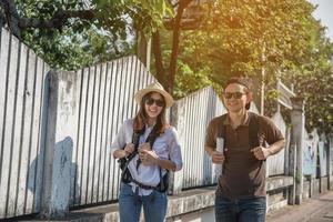 Asian backpack couple tourist holding city map crossing the road - travel people vacation lifestyle concept photo