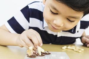 niño asiático comiendo chocolate con galleta felizmente foto