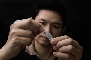 hombre preparando gotas para los ojos curando su dolor ocular con fondo negro - medicina ocular para el cuidado de la salud con el concepto de personas foto