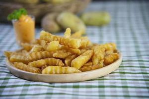 deliciosa patata frita en plato de madera con salsa sumergida - concepto tradicional de comida rápida foto