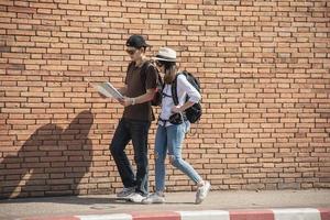 Asian backpack couple tourist holding city map crossing the road - travel people vacation lifestyle concept photo