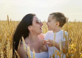 Happy family of mother and infant child walking on wheat field photo