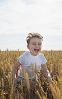 chico lindo caminando por el campo de trigo, haciendo muecas foto