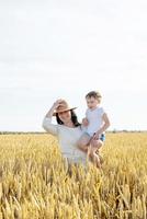 Happy family of mother and infant child walking on wheat field photo