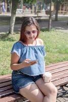 cheerful trendy woman with red hair drinking coffee at park, taking selfie photo