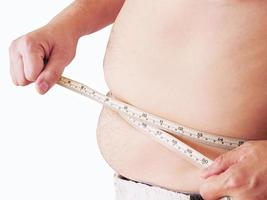 Fat man is measuring his belly using tape meter - dietary health concept photo