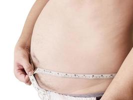 Fat man is measuring his belly using tape meter - dietary health concept photo