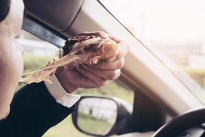Man eating pizza and coffee while driving car dangerously photo