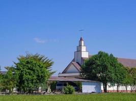 Christian church at green countryside meadow with blue sky and white clouds background photo