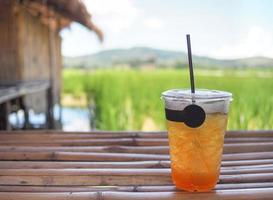 Ice tea placed on bamboo table with rice fields background photo