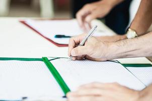 Closeup of people hand with pen at registration point - people in meeting job business event  concept photo