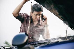 Man try to fix a car engine problem on a local road Chiang mai Thailand - people with car problem transportation concept photo