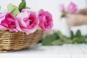 Woman putting pink roses in to white vase happily photo