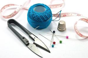 dedal, agujas y bola de hilo azul para coser en un hilo de fondo foto