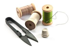 Thimble,needles,spools and scissors for sewing on a background thread photo