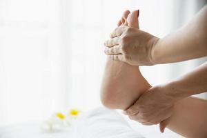 Woman receiving foot massage service from masseuse close up at hand and foot - relax in foot massage therapy service concept photo