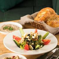 A close up shot of a salad and appetizers near basket of breads photo