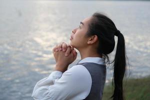 mujer rezando sola al atardecer. mujer reza por la bendición de dios para desear tener una vida mejor. concepto espiritual y religioso. foto