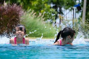 Two cute little girls playing in the pool. Summer lifestyle concept. photo