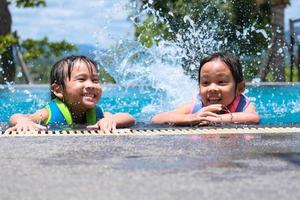 dos lindas niñas jugando en la piscina. concepto de estilo de vida de verano. foto