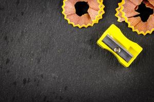 Yellow shavings pencil and yellow pencil sharpener on black background. Horizontal image. photo