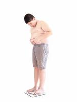 Soft focus of fat boy disappoint his fatness while standing on on weighing machine isolated over white background and included clipping path. photo