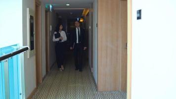 colegas que ingresan a la habitación del hotel. hombre de negocios y mujer de negocios entrando a la habitación del hotel para trabajar. entran a la habitación junto con notebooks y laptops. video