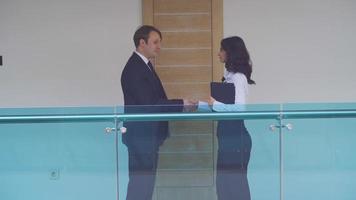 Businessman and businesswoman handshake. Businessman and businesswoman walking in the hallway shaking hands. They are walking together.