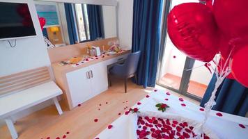 concepto de habitación de hotel para luna de miel. habitación decorada con pétalos de rosa. Globos rojos. concepto romántico de habitación de hotel. video
