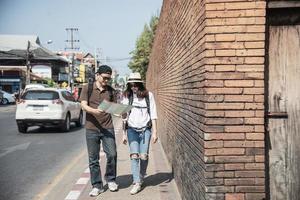 Asian backpack couple tourist holding city map crossing the road - travel people vacation lifestyle concept photo