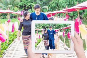 Hand taking Northern Thai style family photo using tablet in local area, Chiang Mai Thailand - Northern people Thai family in traditional costume concept