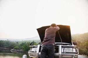 Man try to fix a car engine problem on a local road Chiang mai Thailand - people with car problem transportation concept photo