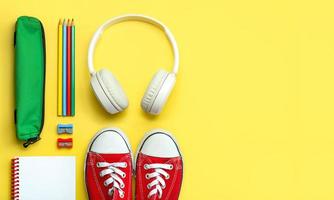 Top view of red sneakers, pencil case, headphones and school supplies with space for text. Back to school concept photo