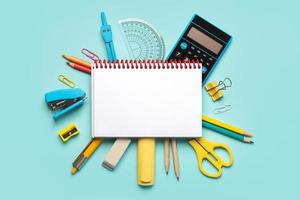 Top view of spiral notepad and school supplies with space for text. Back to school concept photo