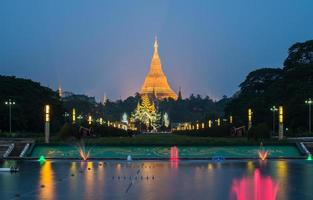 la pagoda de shwedagon con la colorida vista de la fuente desde el parque del pueblo en el municipio de yangon de myanmar por la noche. foto