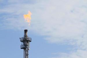 Burning oil flare on a blue sky photo