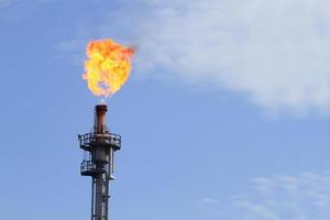 Burning oil flare on a blue sky photo