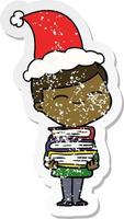 distressed sticker cartoon of a smiling boy with stack of books wearing santa hat vector