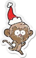 distressed sticker cartoon of a surprised monkey wearing santa hat vector