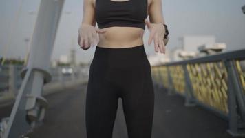 Las atletas asiáticas en cámara lenta usan ropa deportiva en estiramientos negros. calentar antes de correr una maratón práctica todos los días por la mañana en la ciudad con el río antes de la maratón. video
