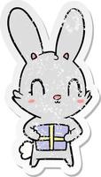 distressed sticker of a cute cartoon rabbit with present vector