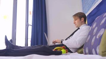 man aan het werk met zijn computer in hotelkamer. fruitschaal. man voorbereiden op zakelijke bijeenkomst in hotelkamer. werken op de computer. video