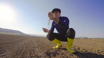 The farmer takes the soil with his palm and pours it. Farmer scooping soil in farmland. He takes the soil and pours it down from his palm. video