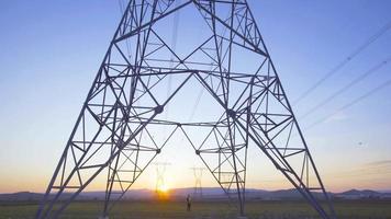 Engineer walking between electrical towers. Engineer with laptop in hand walks between power poles and inspects. He takes notes on the laptop and looks at the poles. video