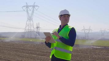 irrigation des terres agricoles et ingénieur. les terres agricoles sont irriguées par un système de gicleurs. l'ingénieur prend des notes sur la tablette et travaille. agriculture moderne et technologique. video