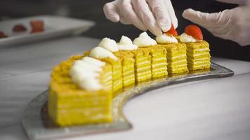 The chef puts strawberries on the cakes. The chef is preparing a dessert serving plate. He puts a strawberry on top of the cakes. video