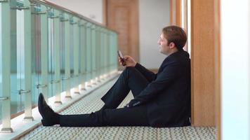 Businessman using phone. Corridor. Businessman sitting on the floor in the hallway is using the phone. Unhappy and nervous. video