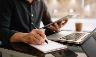 view of young professional businessman writing his idea concepts on notebook while working on his project photo