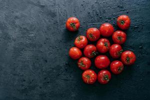 Top view of fresh red tomatoes wet after rain. Copy space aside. Organic vegetables. Raw food. Healthy nutrition concept. Ripe juicy heirloom tomatoes photo